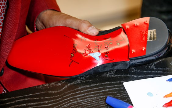 Christian Louboutin signs shoes | Source: Isa Foltin/Getty Images